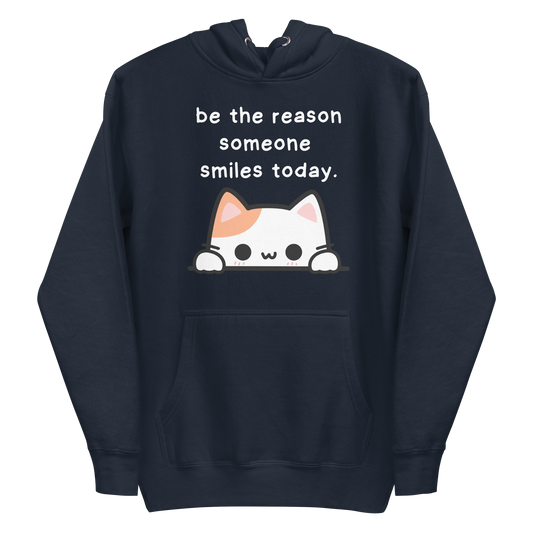 A navy blazer men's premium hoodie featuring a graphic of a cute white and orange & white cat peeking over a ledge. Above the cat is the text 'be the reason someone smiles today'.