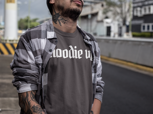Man wearing a dark gray t-shirt with 'hoodie up' text, standing outdoors.