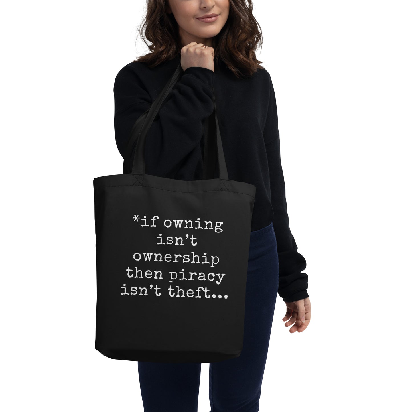 A woman holding a black organic cotton tote bag featuring the text quote 'If owning isn't ownership then piracy isn't theft' regarding digital rights.