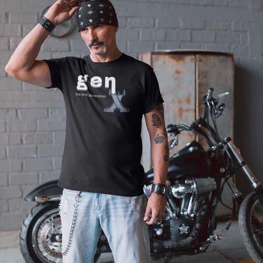 A man standing in front of a chopper style motorcycle. He is wearing jeans and leather wrist bracelets along with a black t-shirt featuring 'gen x the feral generation' text. The 'x' is formed by two, overlaid 1970's style playground slides.