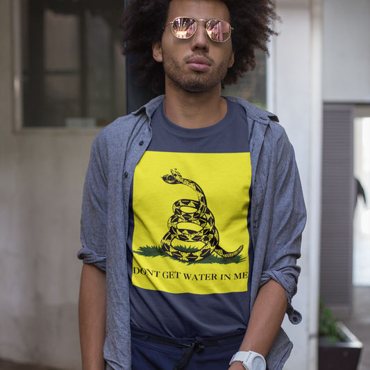 A man wearing mirrored sunglasses and an unbuttoned overshirt wearing a white watch with a white strap. He is also wearing a blue t-shirt with a yellow Gadsden Flag style graphic featuring a snake on a bed of grass. Under the bed of grass is the all-caps text, 'DON'T GET WATER IN ME'. The snakes jaws are open to reveal a watch face.