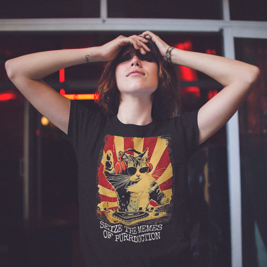 A woman standing against a darkened background with her arms raised and bent at the elbows, resting her hands against her forehead. Her head is tilted slight back and she has a mischevious grin. She is wearing a black t-shirt with a graphic of a cat DJing against a vintage propaganda style poster background, with the text "SEIZE THE MEMES OF PURRDUCTION" at the bottom