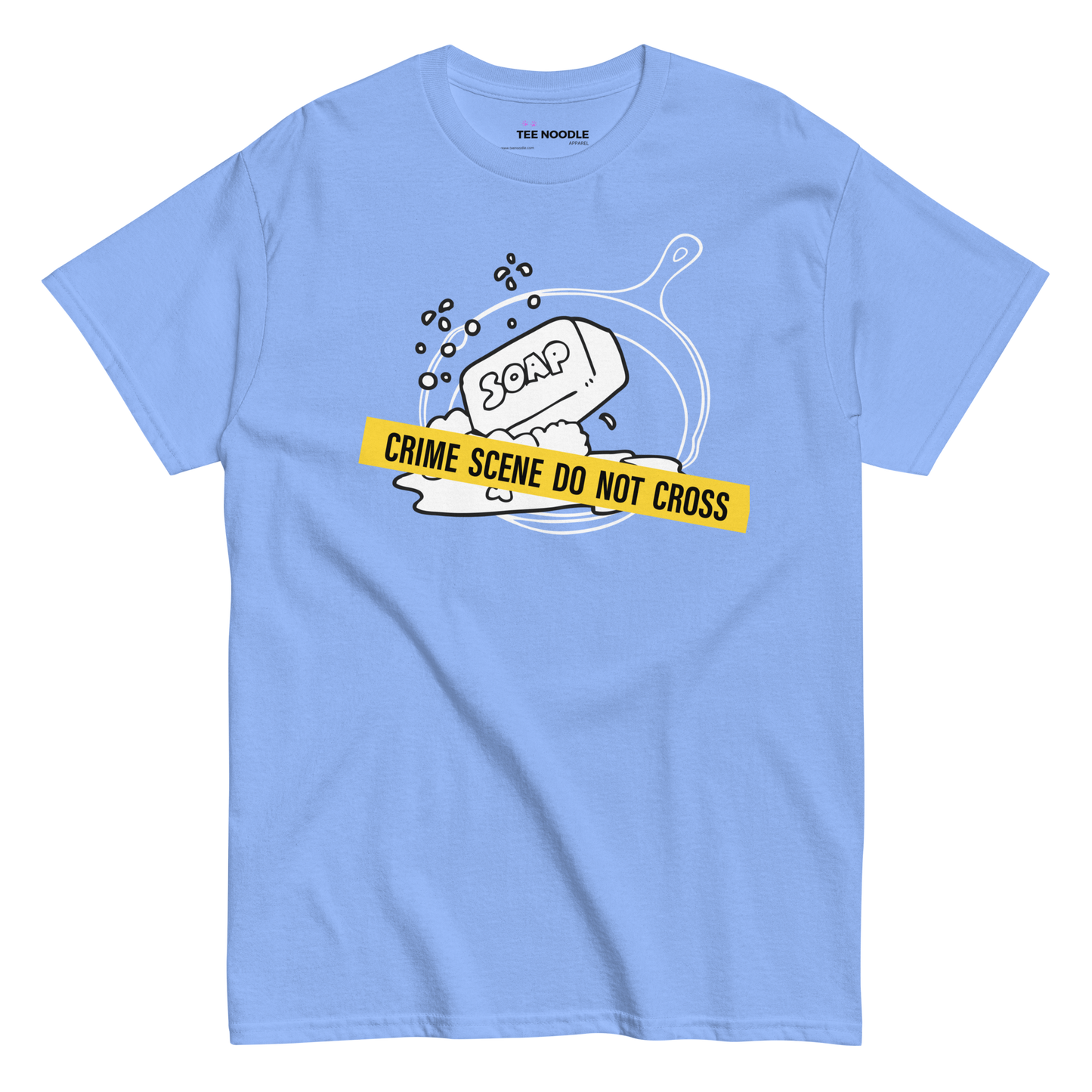 A carolina blue t-shirt featuring a white line-art graphic of a cast iron skillet filled with bubbles and a bar of soap. A yellow strip of tape across the front reads 'CRIME SCENE DO NOT CROSS'.