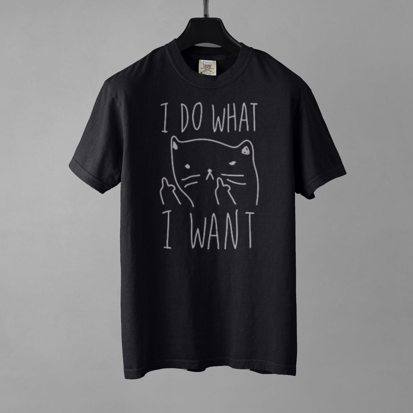 A black t-shirt with a graphic of a cat with anthropomorphic middle fingers raised to the viewer and text 'I DO WHAT I WANT' on a gray background