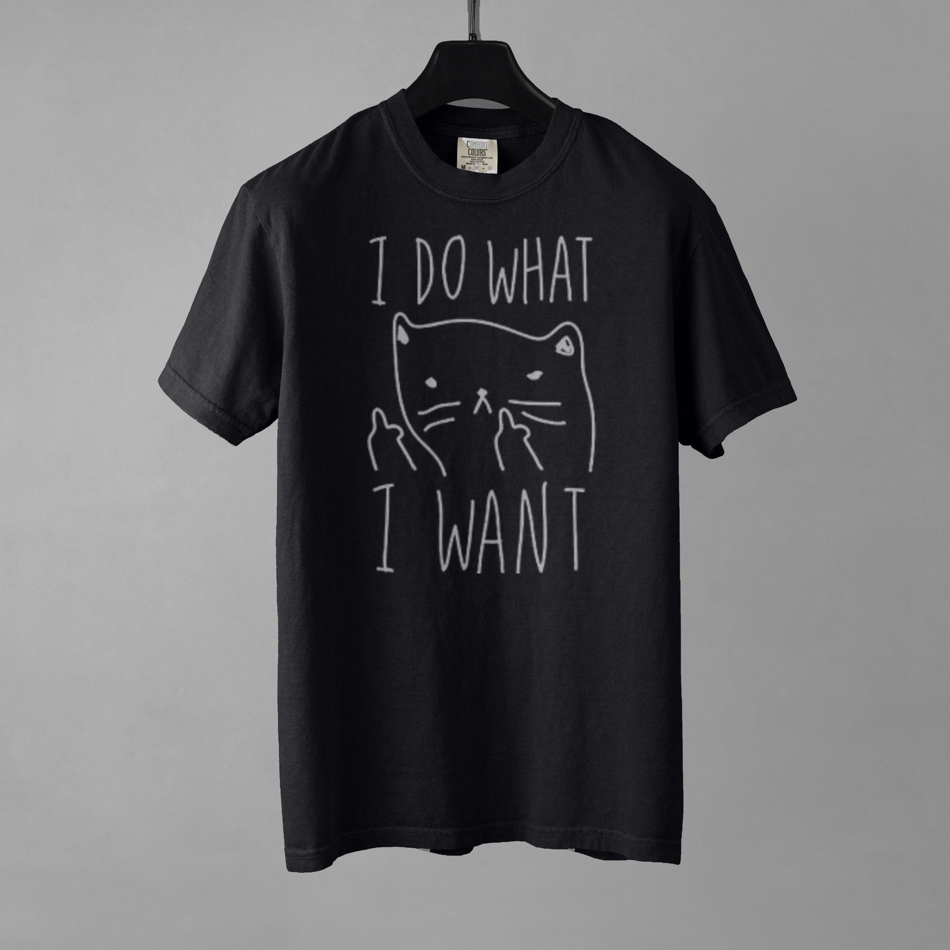 A black t-shirt with a graphic of a cat with anthropomorphic middle fingers raised to the viewer and text 'I DO WHAT I WANT' on a gray background