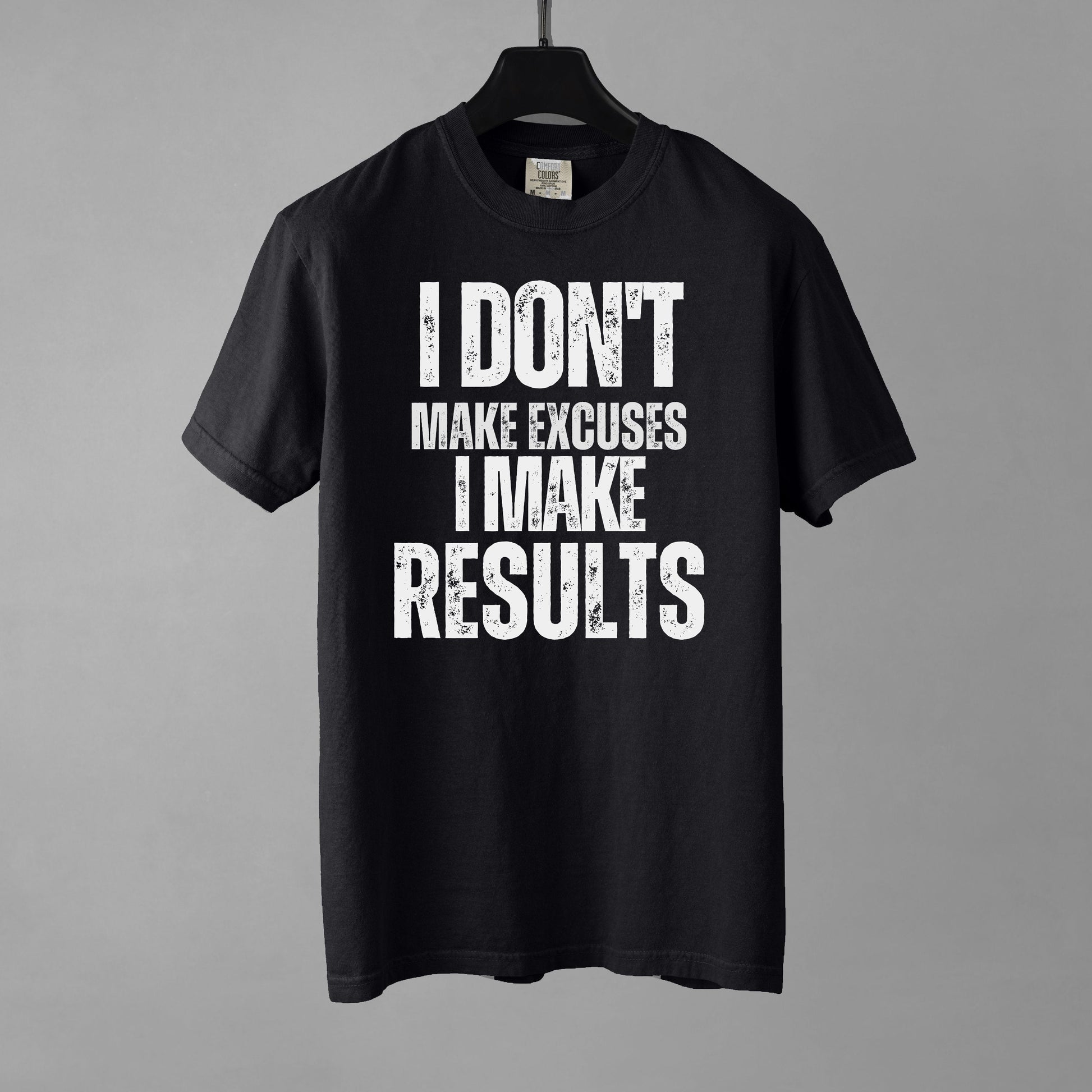 A black t-shirt with bold, all-caps, distressed text that reads 'I DON'T MAKE EXCUSES I MAKE RESULTS', on a gray background.