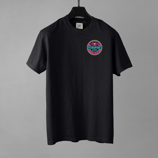A black Comfort Colors 1717 T-shirt with a small Spicoli Hydroponics retro surf-style logo printed on the left chest. The garment is resting on a black hanger against a grey background.