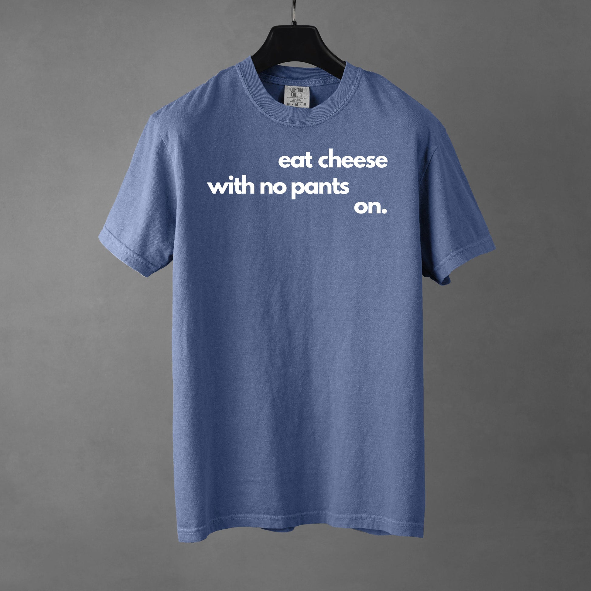 A blue t-shirt with text that reads 'eat cheese with no pants on' on a gray background