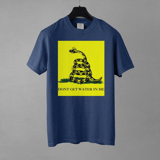 A blue t-shirt with a yellow Gadsden Flag style graphic featuring a snake on a bed of grass. Under the bed of grass is the all-caps text, 'DON'T GET WATER IN ME'. The snakes jaws are open to reveal a watch face. 