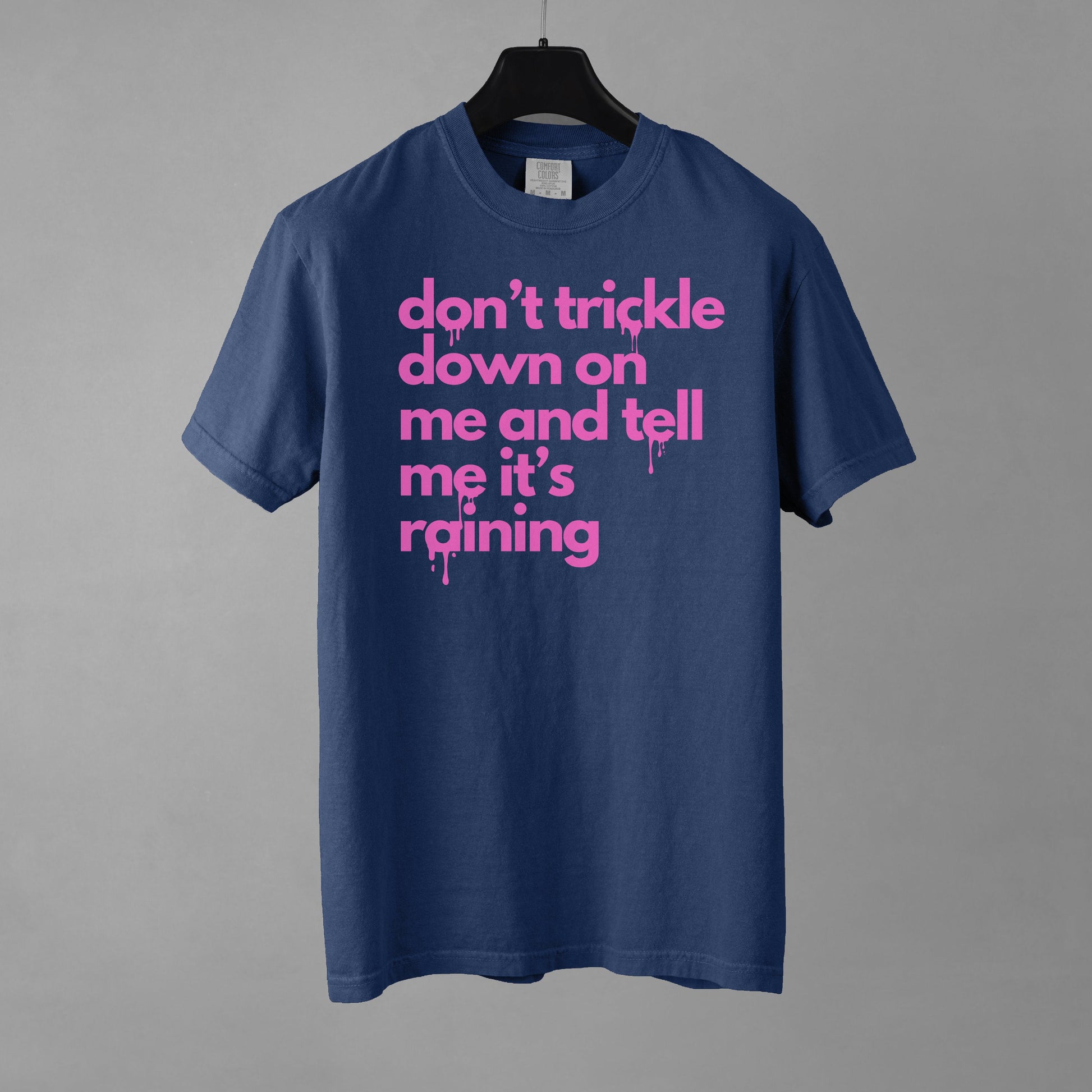 A navy colored t-shirt with pink text reading 'don't trickle down on me and tell me it's raining' in lower case letters with a dripping effect on some of the letters.
