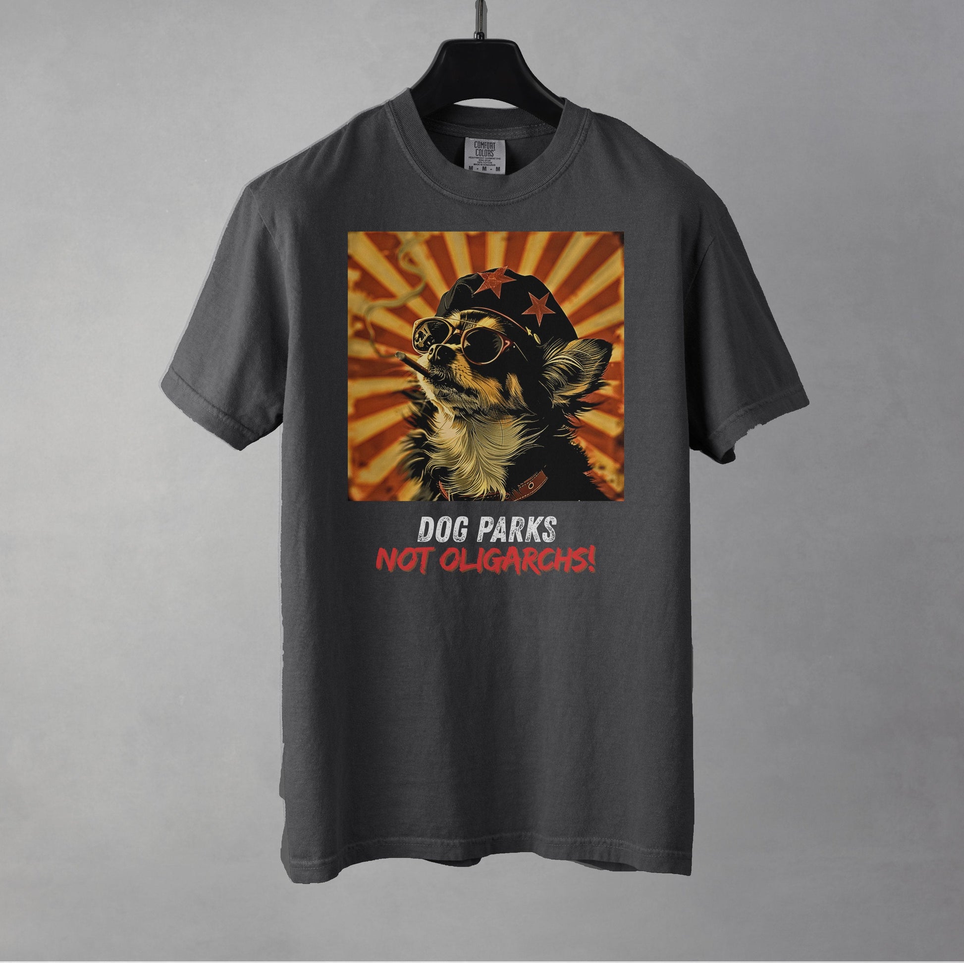 A pepper colored women's t-shirt with a graphic of a Chihuahua wearing sunglasses and a beret against a 50's style propaganda background with bold all-caps text underneath that reads "DOG PARKS NOT OLIGARCHS".