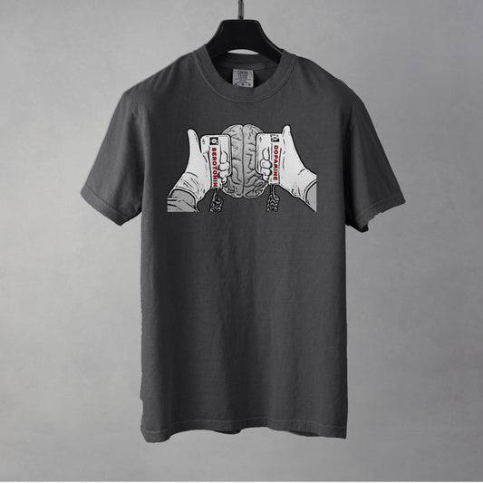 A pepper colored t-shirt with a black and white line drawing graphic on the chest of a brain beneath two hands holding defibrillating paddles. The left paddle is labelled Serotonin and the right paddle is labelled Dopamine.  