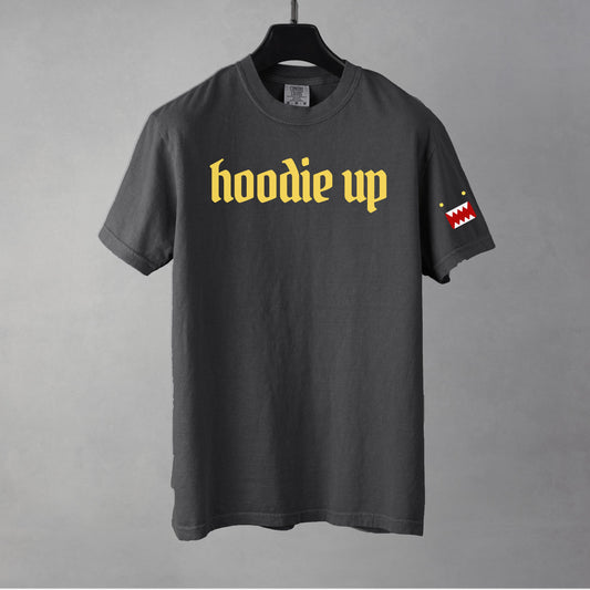 A pepper colored t-shirt with yellow text 'hoodie up' on a gray background