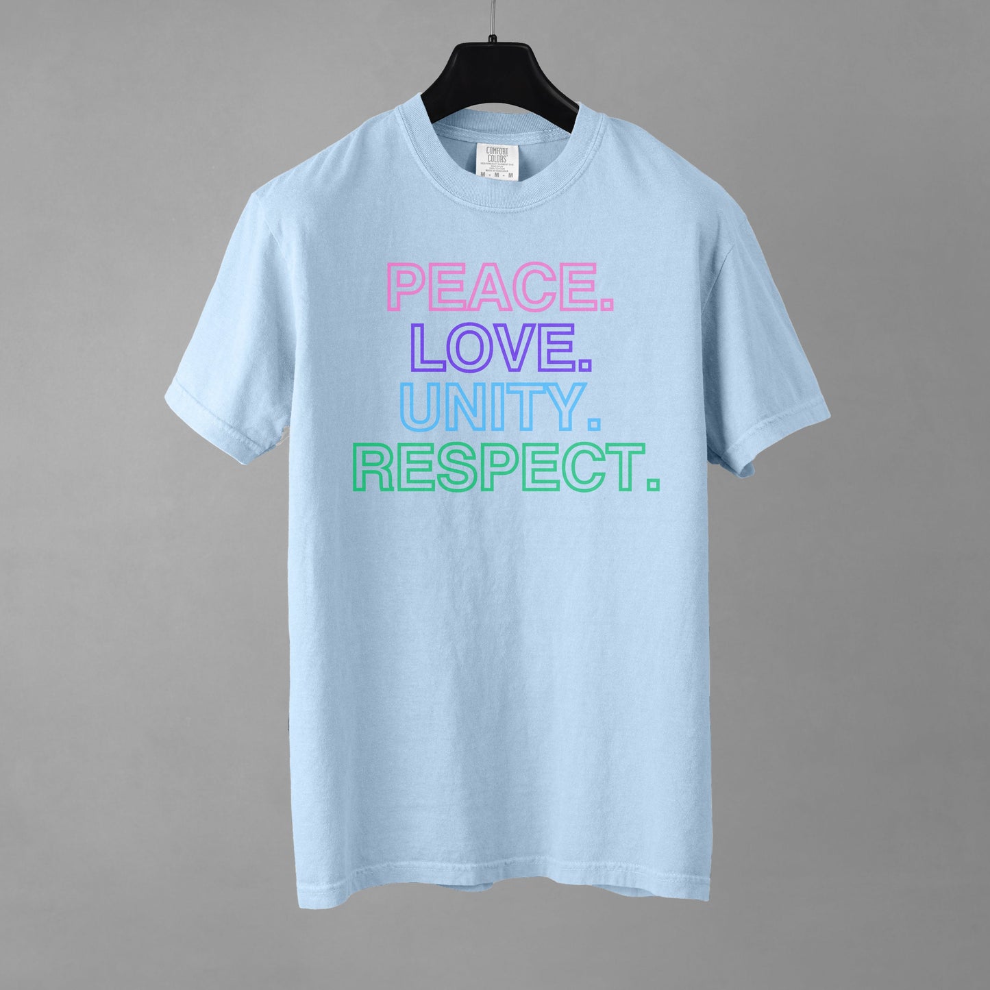 A light blue t-shirt with colorful text stacked in descending order that reads 'PEACE. LOVE. UNITY. RESPECT.' on a gray background.