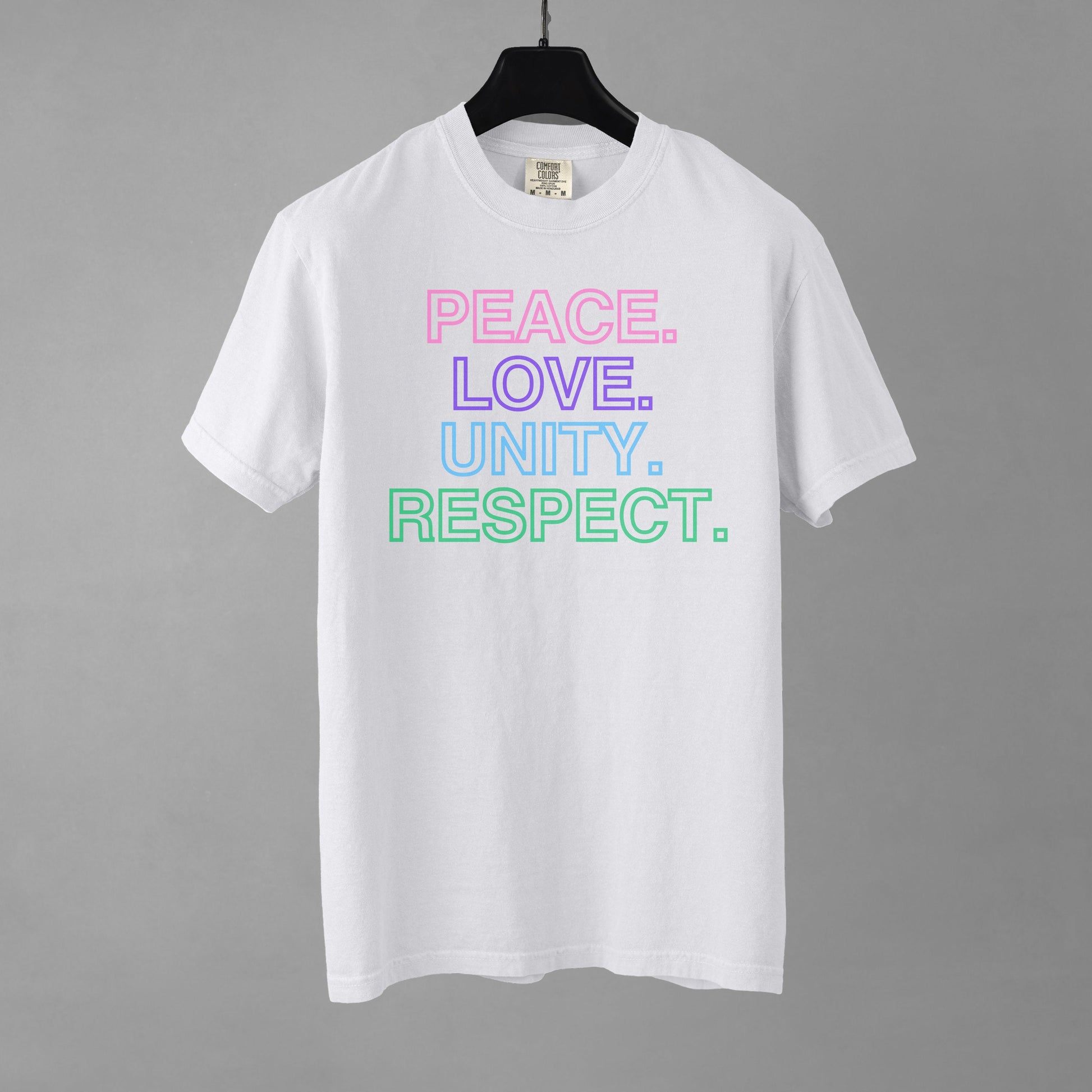 A white t-shirt with colorful text stacked in descending order that reads 'PEACE. LOVE. UNITY. RESPECT.' on a gray background.