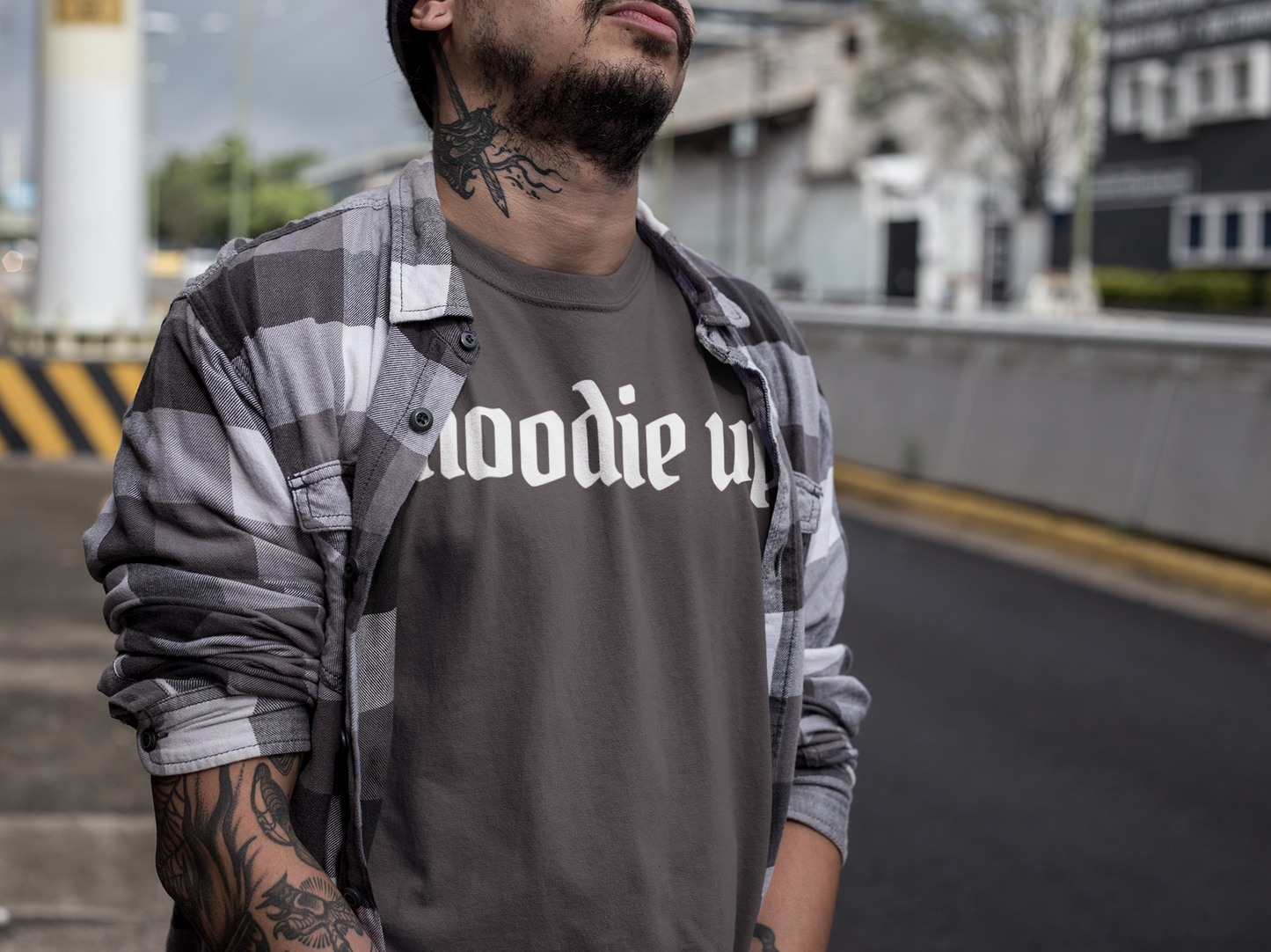 Man wearing a dark gray t-shirt with 'hoodie up' text, standing outdoors.