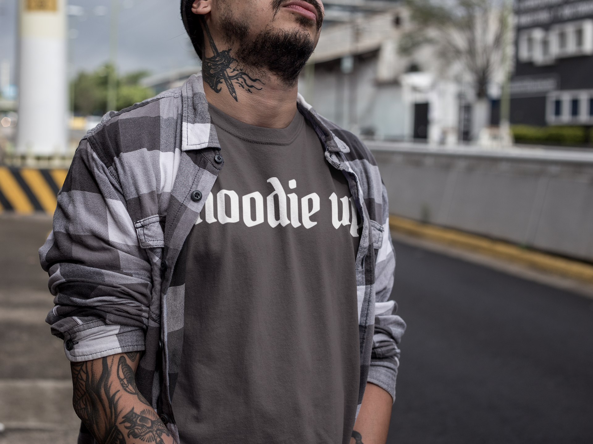 Man wearing a dark gray t-shirt with 'hoodie up' text, standing outdoors.