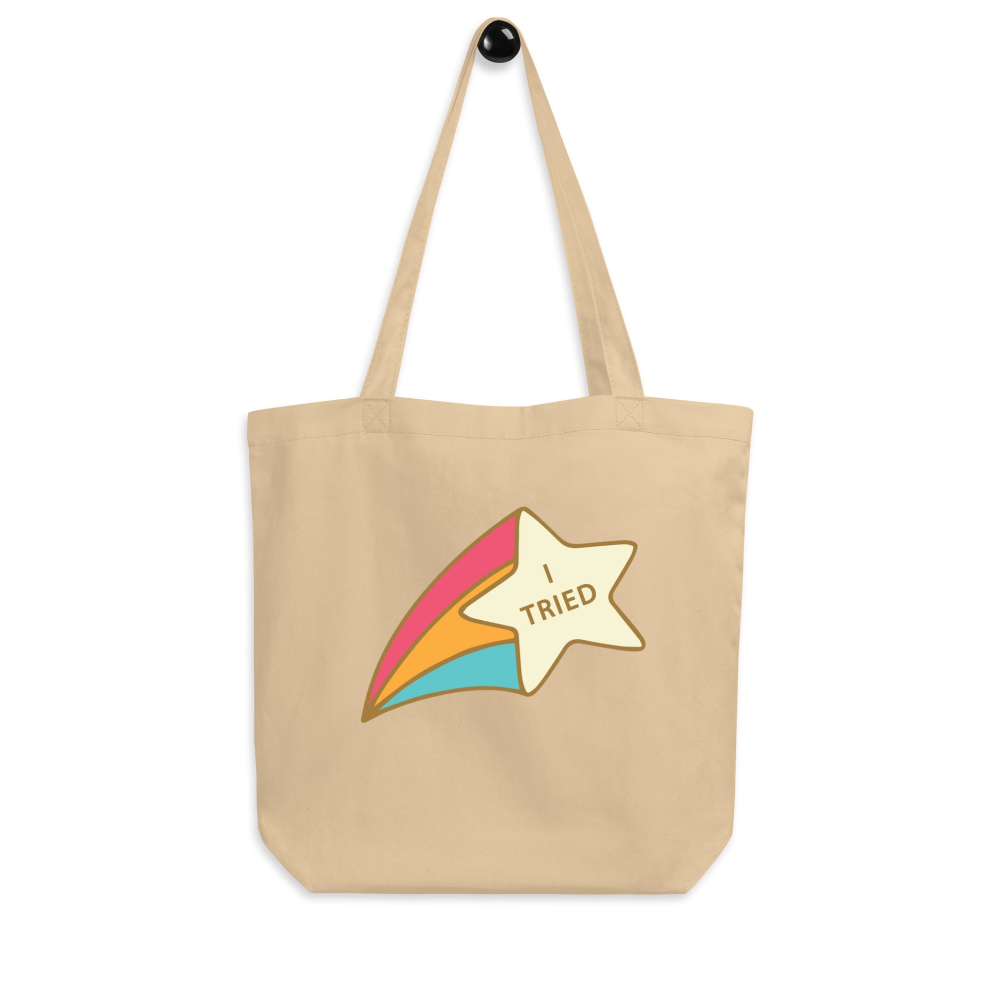 An oyster beige organic cotton tote bag featuring a retro cartoon shooting star graphic with a rainbow tail. Inside the gold star is the text: 'I TRIED'.