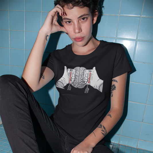 Person wearing a black t-shirt with a graphic design, sitting on a blue tiled floor.