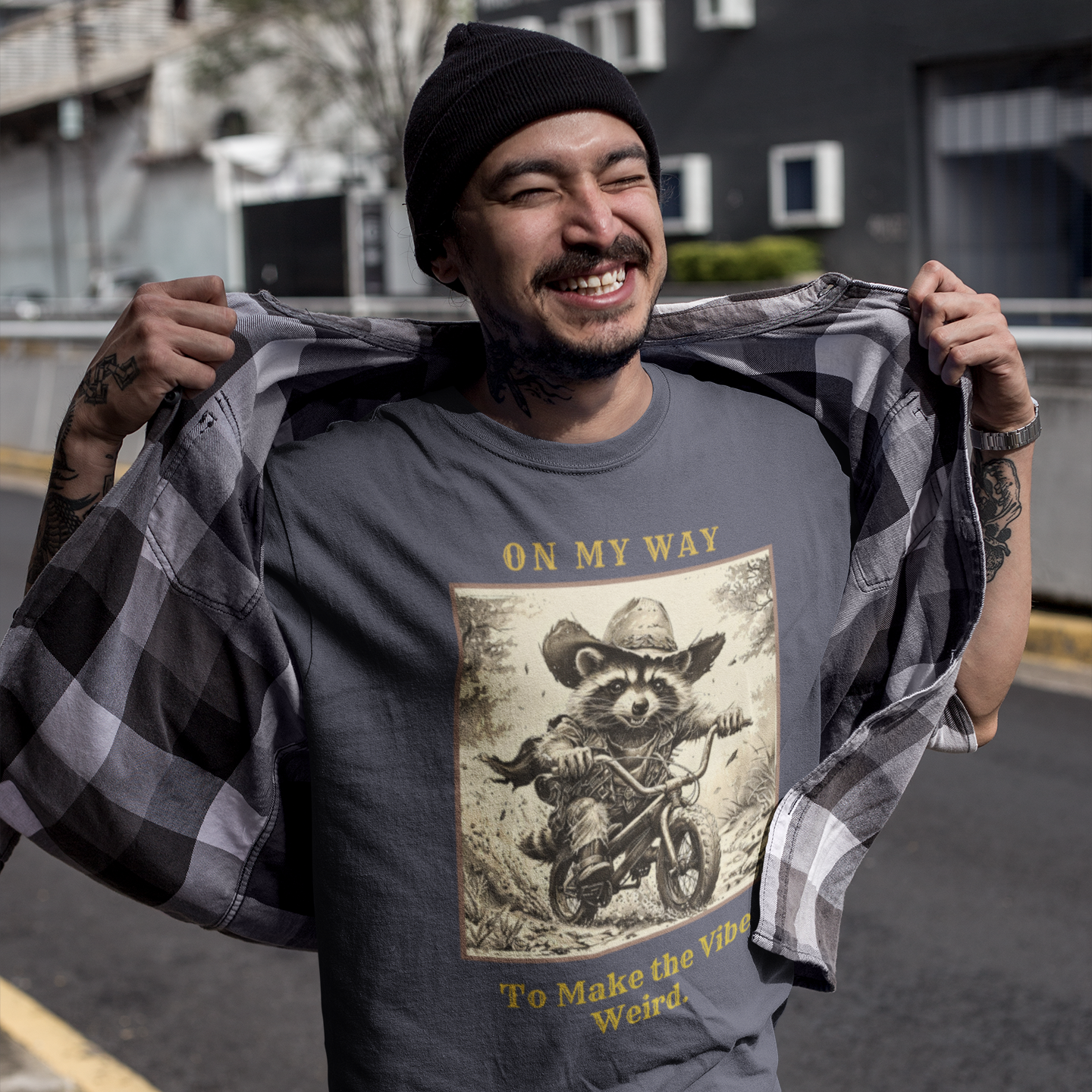 Man wearing a t-shirt with a graphic design and text, holding a checkered shirt.