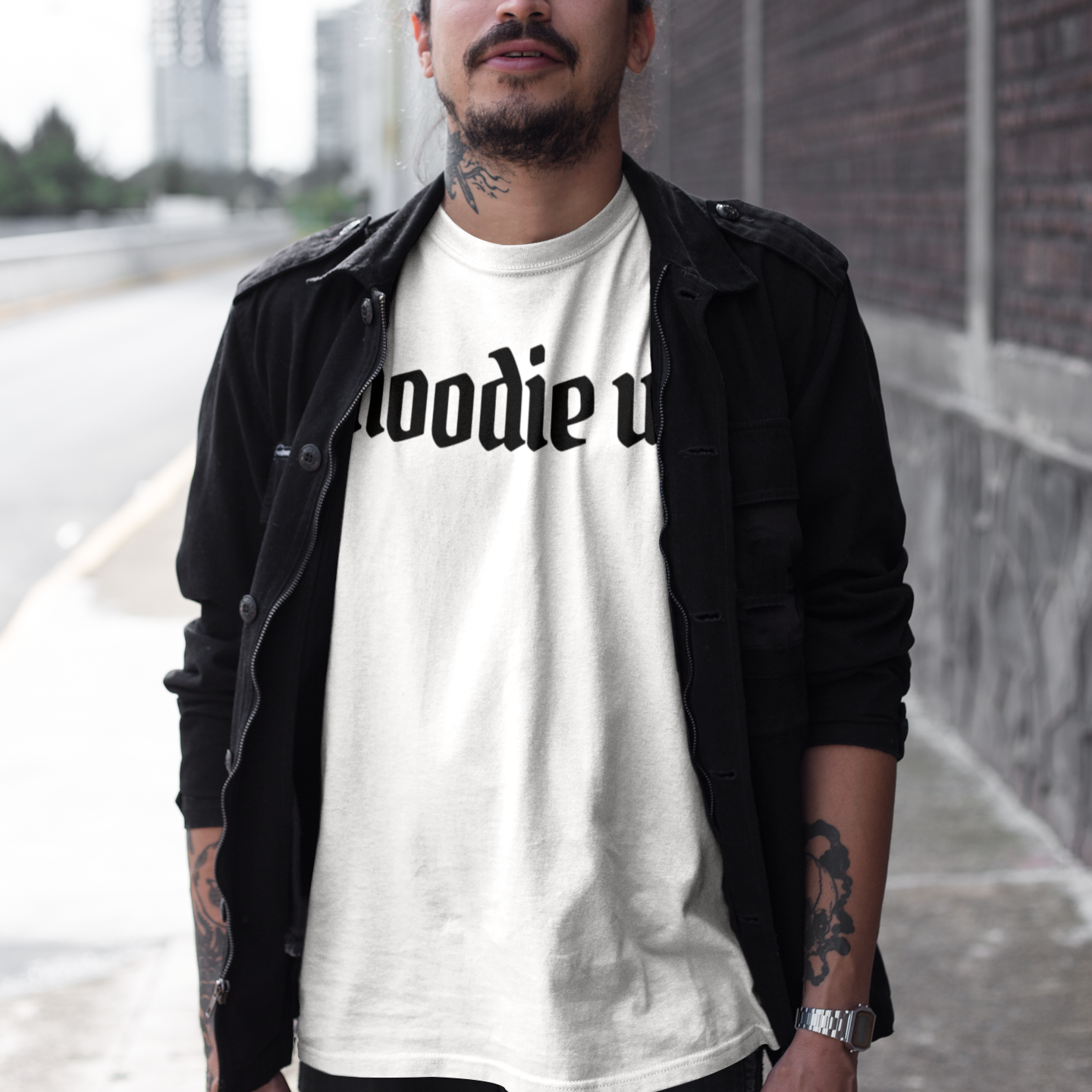 Man wearing a white t-shirt with text, standing outdoors near a building.