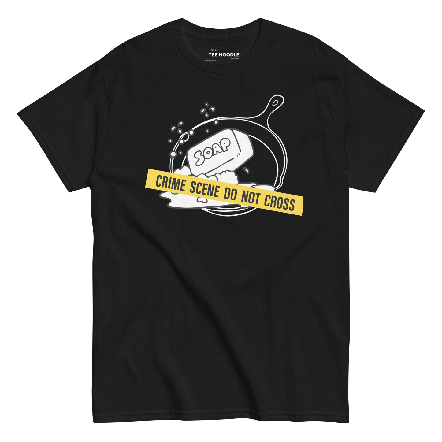 A black t-shirt featuring a white line-art graphic of a cast iron skillet filled with bubbles and a bar of soap. A yellow strip of tape across the front reads 'CRIME SCENE DO NOT CROSS'.