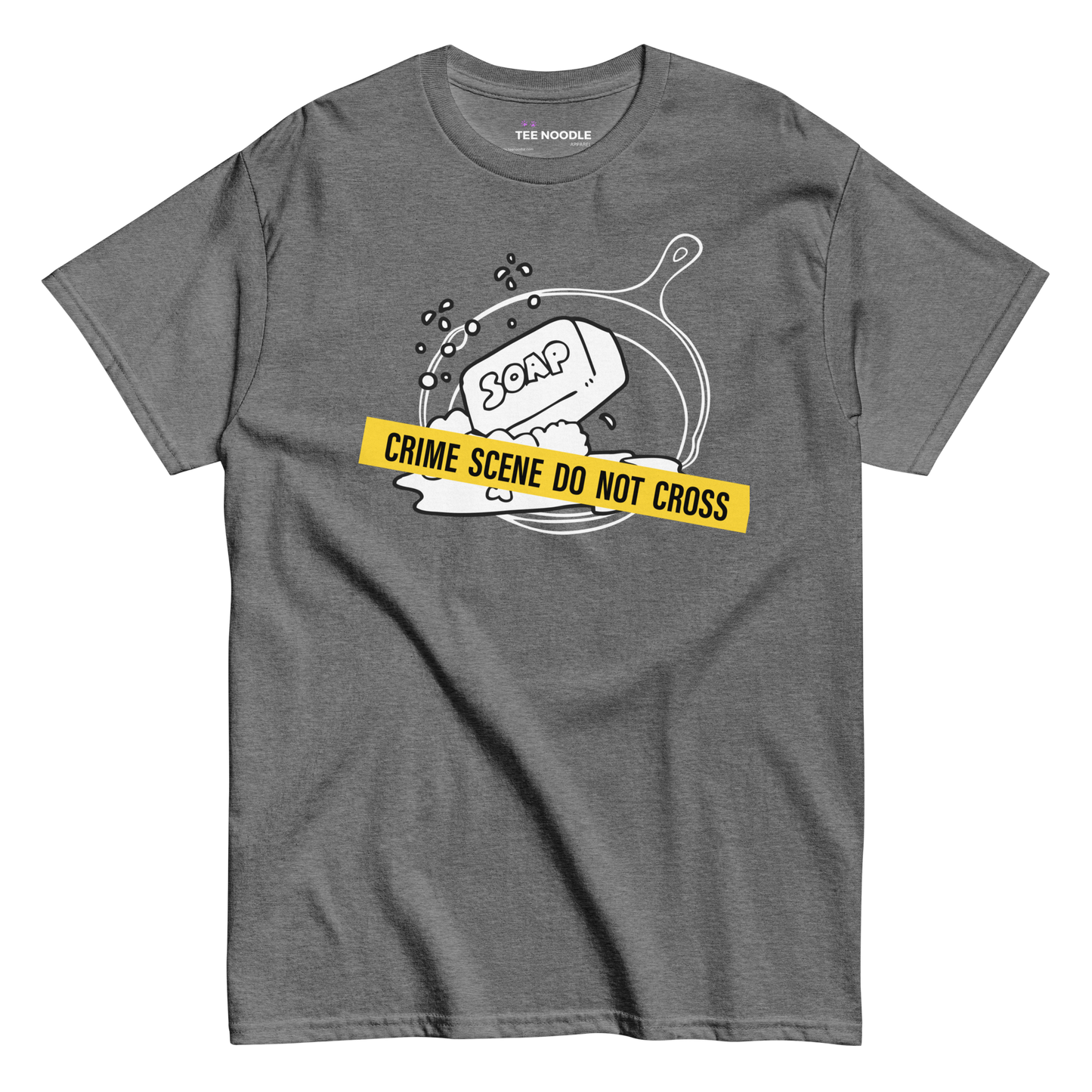 A graphite heather t-shirt featuring a white line-art graphic of a cast iron skillet filled with bubbles and a bar of soap. A yellow strip of tape across the front reads 'CRIME SCENE DO NOT CROSS'.