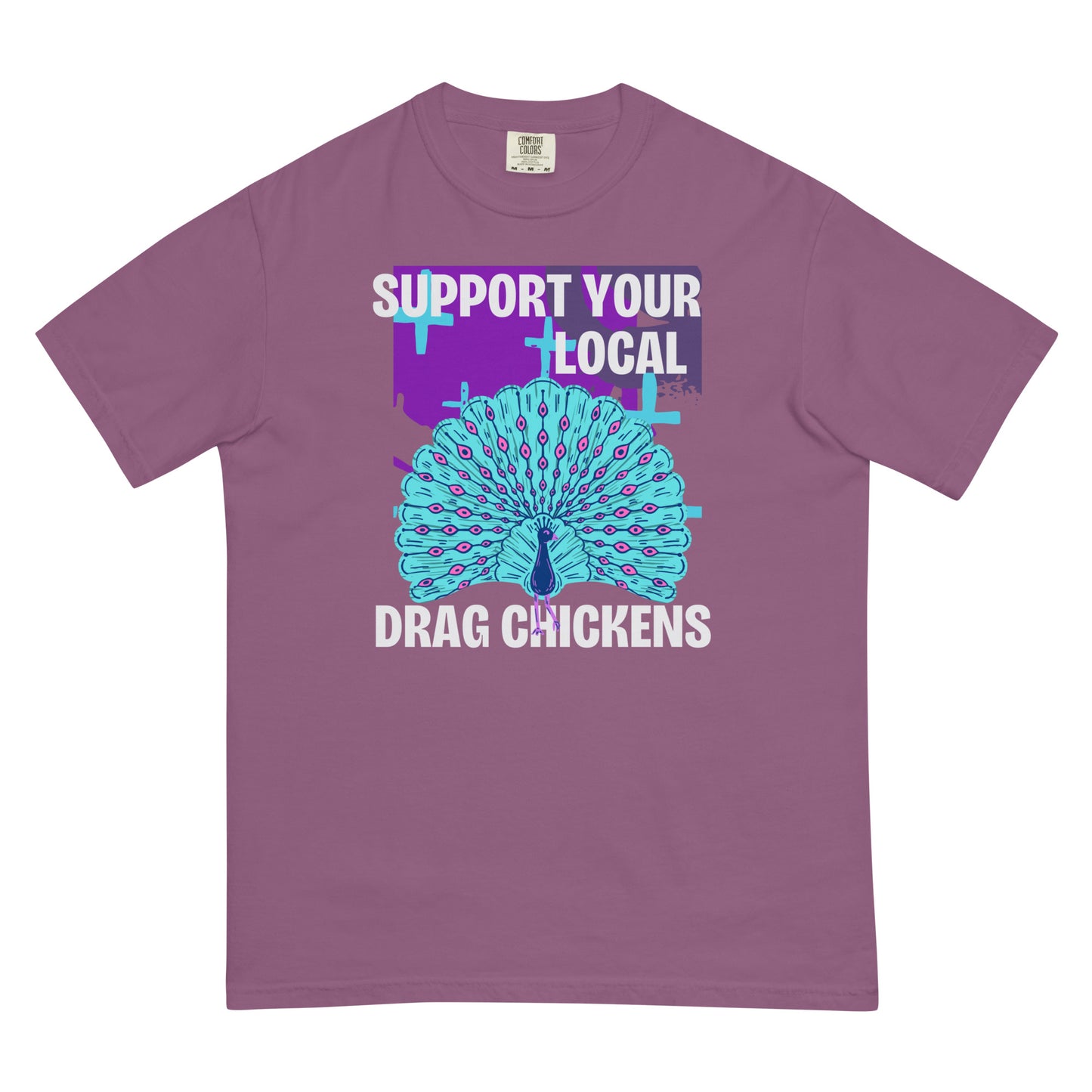 A berry colored short-sleeve crewneck t-shirt featuring a stylized graphic of a peacock with its tail feathers fully fanned out. The peacock is light blue with pink eye details, set against a distressed purple background block with light blue plus signs. Above the peacock is bold white text reading 'SUPPORT YOUR LOCAL', and below it reads 'DRAG CHICKENS'.