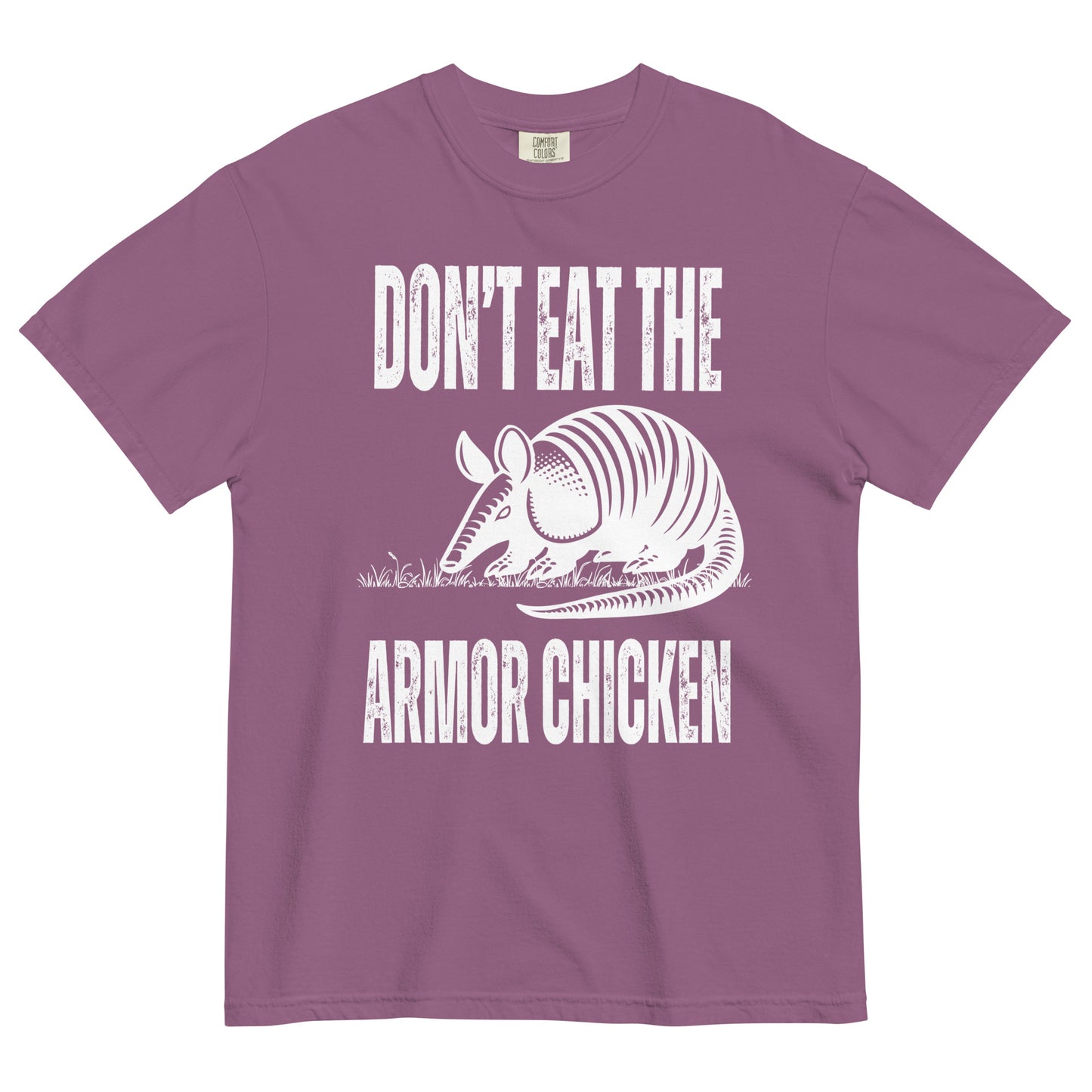 A berry colored t-shirt with bold, all-caps, distressed white text that says 'DONT EAT THE ARMOR CHICKEN'. The text is separated into two lines by a white, line drawing graphic of an armadillo eating grass. 
