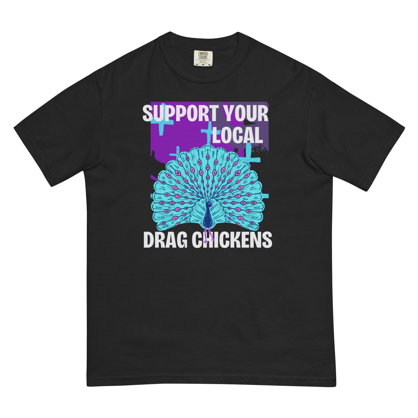 A black colored short-sleeve crewneck t-shirt featuring a stylized graphic of a peacock with its tail feathers fully fanned out. The peacock is light blue with pink eye details, set against a distressed purple background block with light blue plus signs. Above the peacock is bold white text reading 'SUPPORT YOUR LOCAL', and below it reads 'DRAG CHICKENS'.