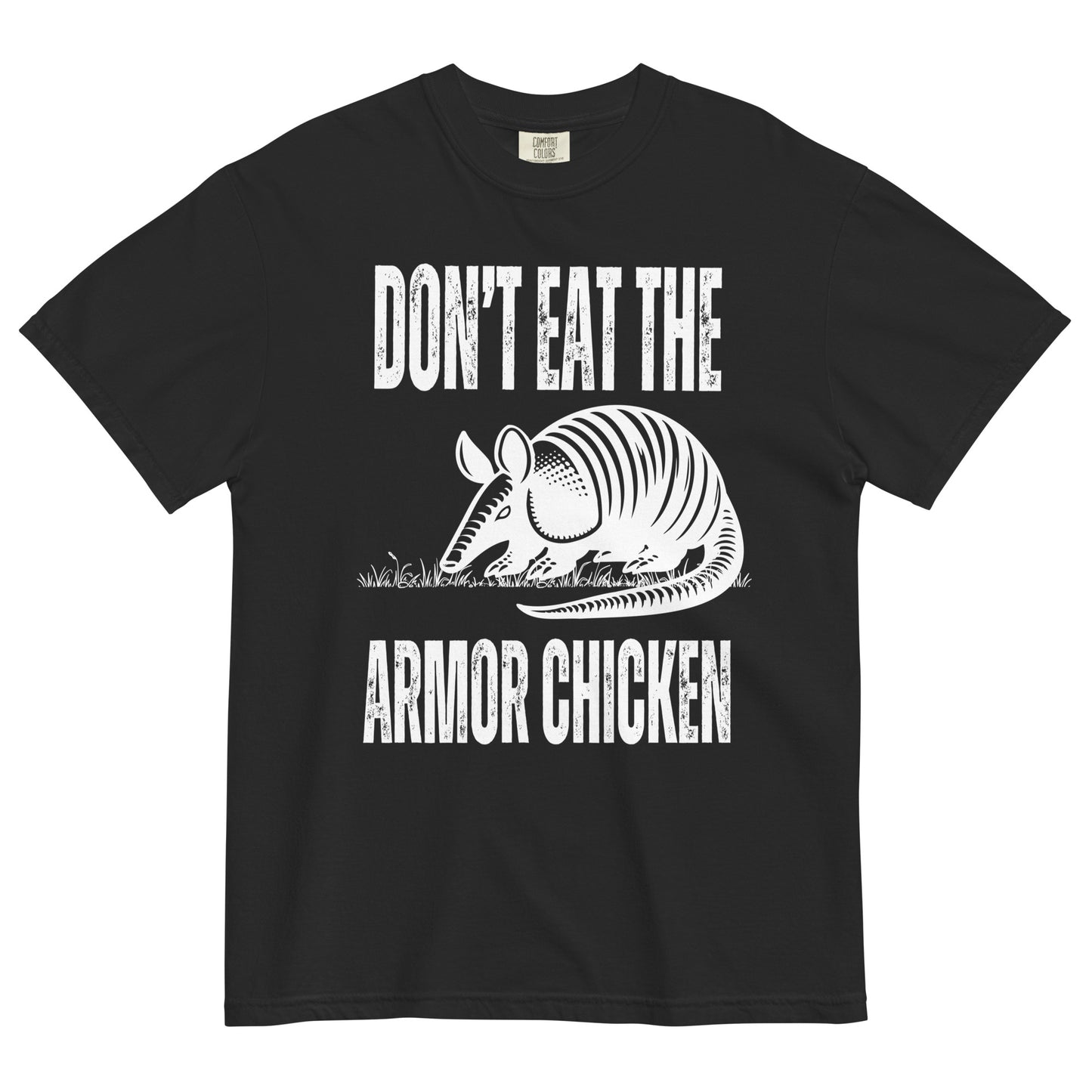 A black t-shirt with bold, all-caps, distressed white text that says 'DONT EAT THE ARMOR CHICKEN'. The text is separated into two lines by a white, line drawing graphic of an armadillo eating grass. 