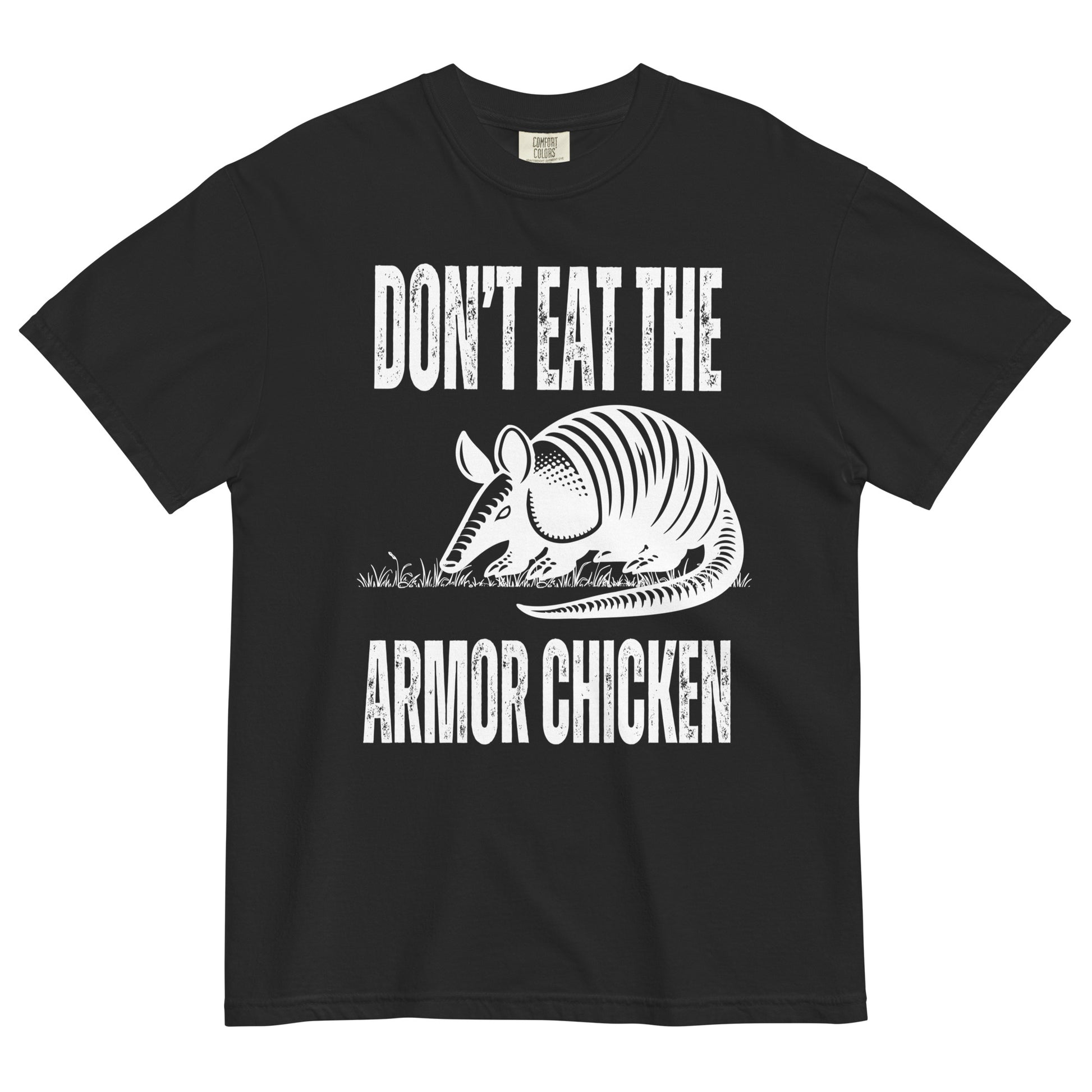 A black t-shirt with bold, all-caps, distressed white text that says 'DONT EAT THE ARMOR CHICKEN'. The text is separated into two lines by a white, line drawing graphic of an armadillo eating grass. 