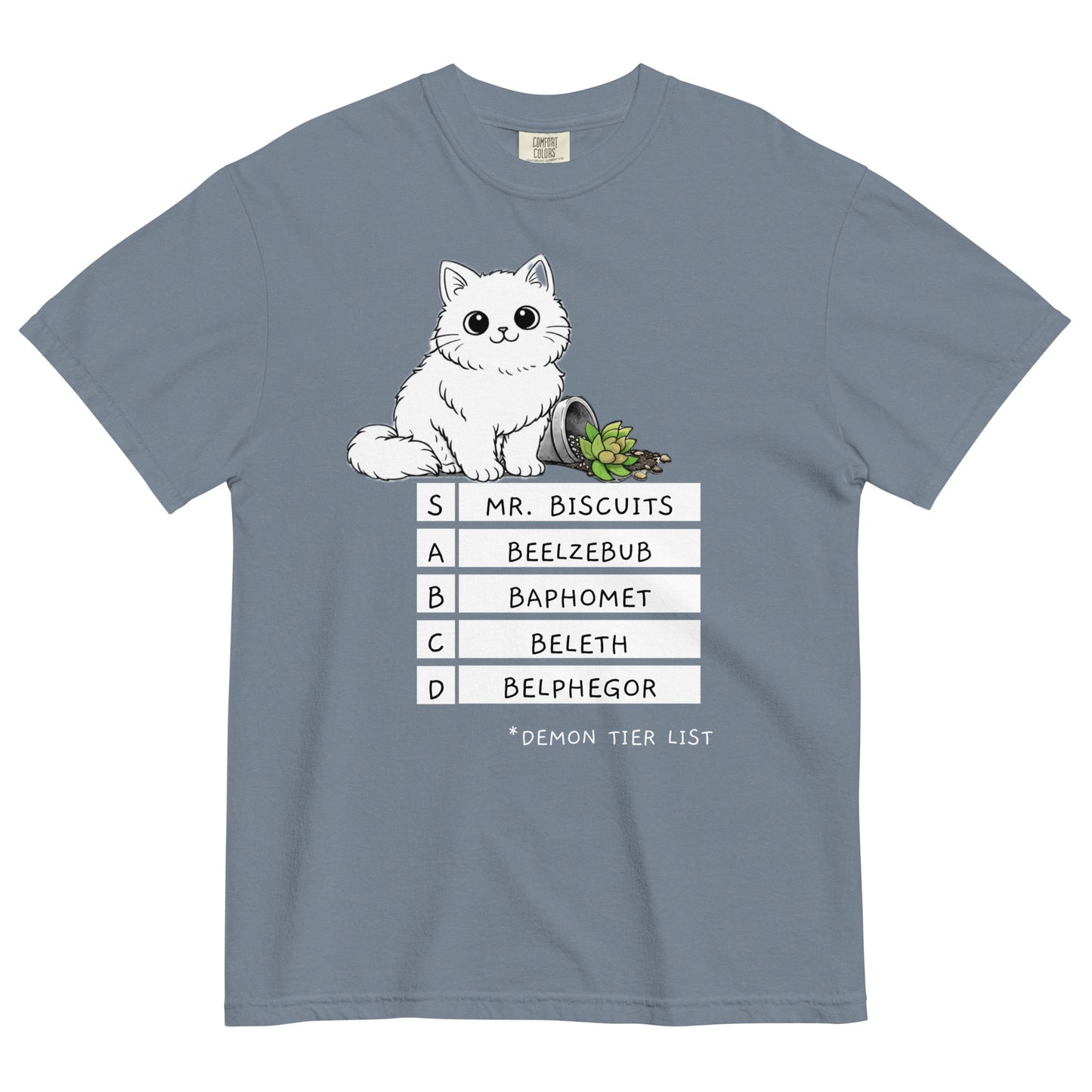 A blue jean colored t-shirt with a graphic of a white, fluffy kitten standing behind a knocked over plant. Beneath the cat is a 'Demon Tier List' with the cat 'Mr. Biscuits' listed atop the list in the S tier position.