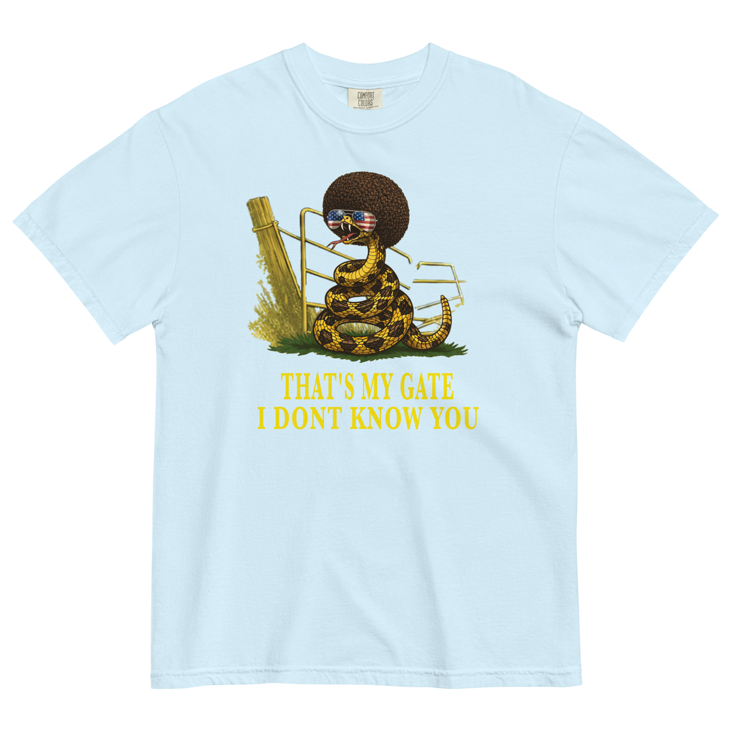 A chambray colored graphic t-shirt featuring a coiled rattlesnake, in front of a broken gate, with a large brown afro and flag-mirrored sunglasses above yellow text that reads "THAT'S MY GATE I DONT KNOW YOU."