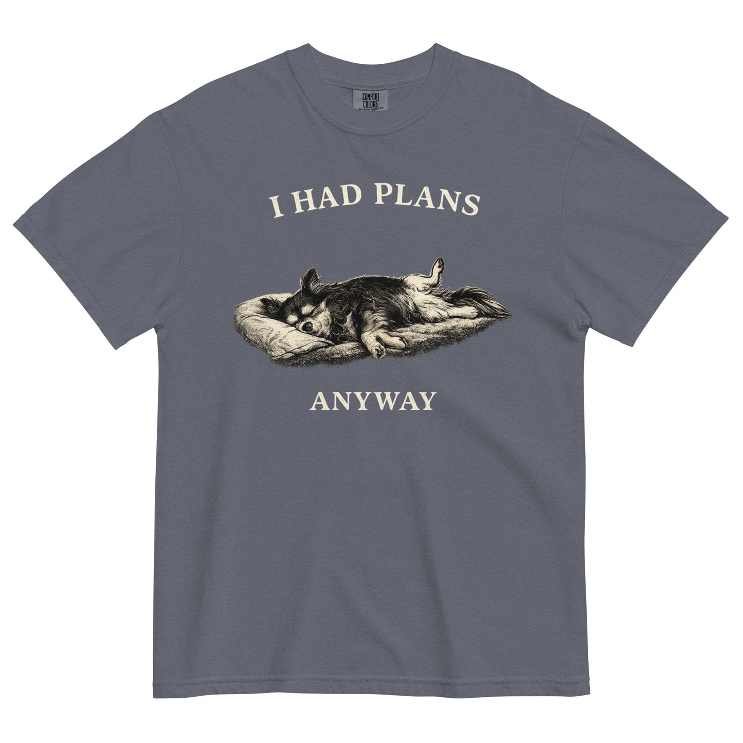 A denim colored t-shirt featuring a monochrome illustration of a long-haired Chihuahua sleeping deeply on its back in a dog bed, with rear legs splayed open and forepaws crossed. Above the illustration in bold, white capital letters is the text 'I HAD PLANS', and below it reads 'ANYWAY'.