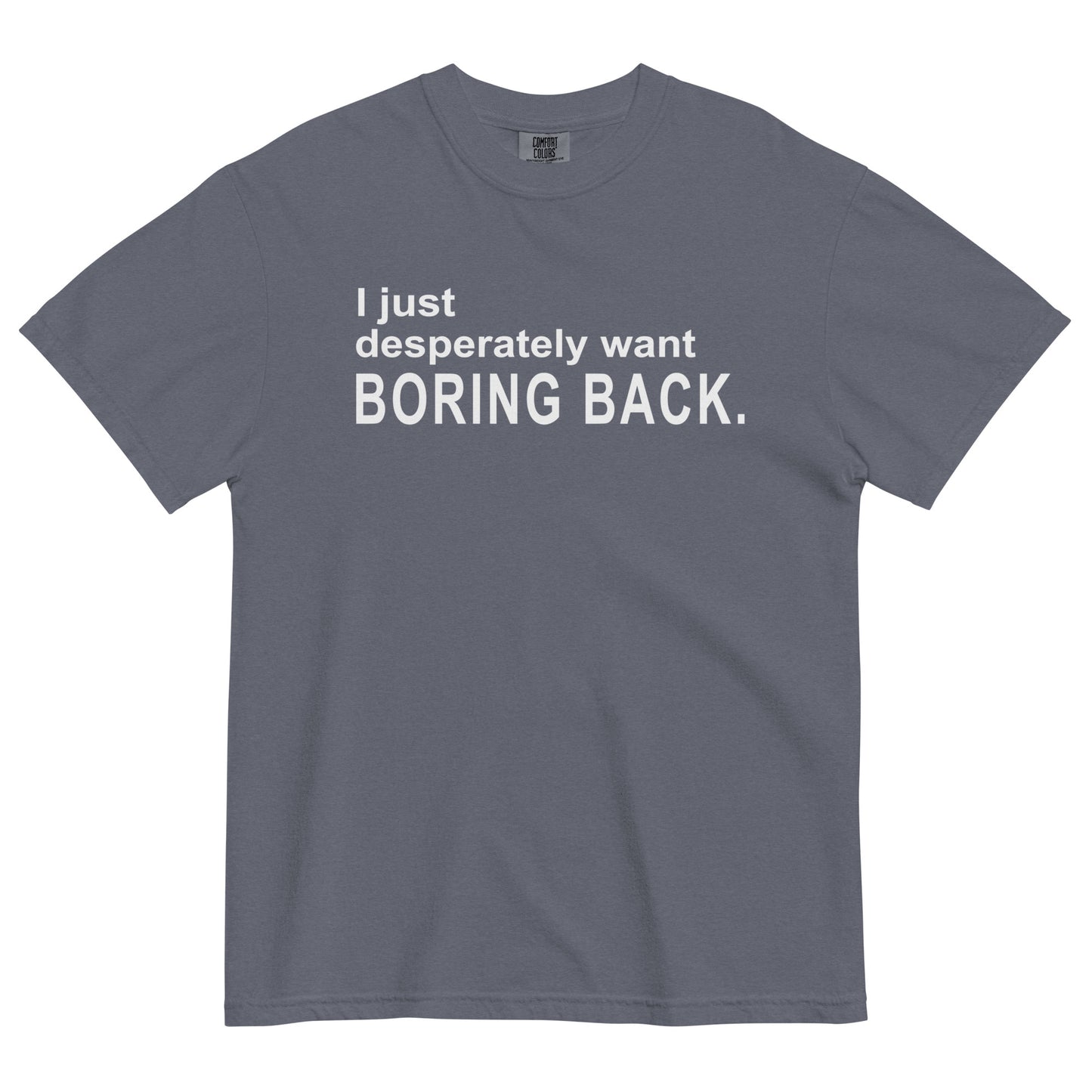 A denim colored graphic t-shirt with the words "I just desperately want BORING BACK." printed in bold white sans-serif text across the chest.
