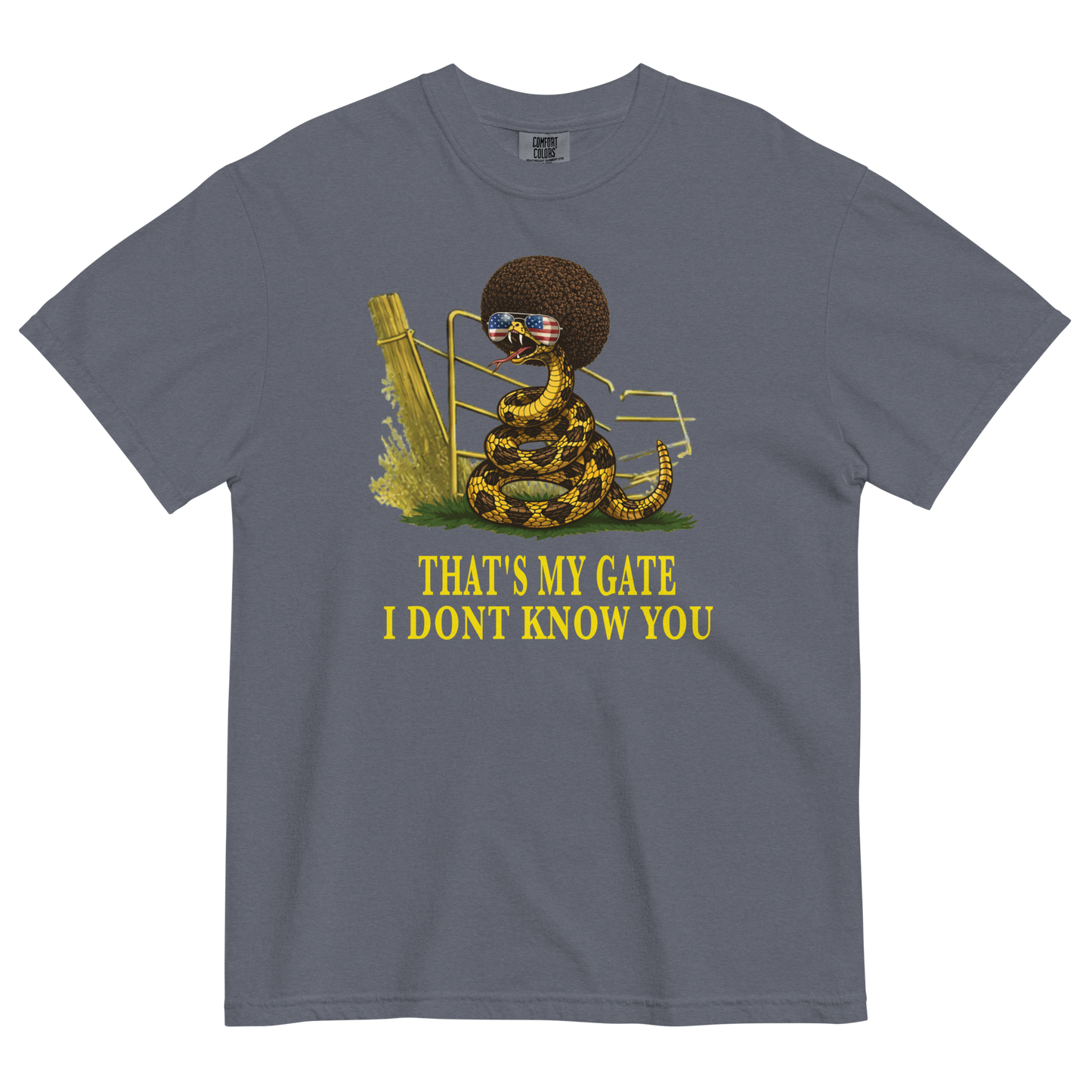 A denim colored graphic t-shirt featuring a coiled rattlesnake, in front of a broken gate, with a large brown afro and flag-mirrored sunglasses above yellow text that reads "THAT'S MY GATE I DONT KNOW YOU."