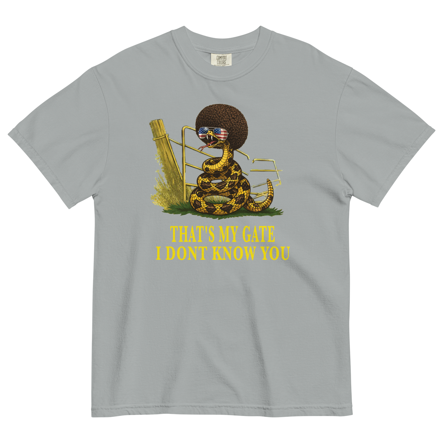A granite colored graphic t-shirt featuring a coiled rattlesnake, in front of a broken gate, with a large brown afro and flag-mirrored sunglasses above yellow text that reads "THAT'S MY GATE I DONT KNOW YOU."