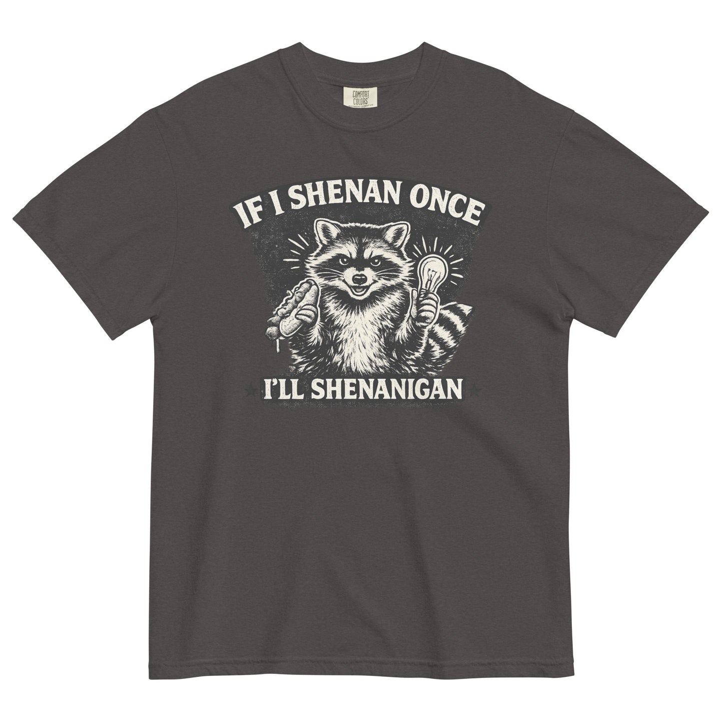 A graphite colored short-sleeve crewneck t-shirt featuring a distressed black and white illustration of a smiling raccoon holding a hot dog in one paw and a glowing lightbulb in the other. Arched above the raccoon is text that reads 'IF I SHENAN ONCE', and below the raccoon is text flanked by stars that reads 'I'LL SHENANIGAN'.