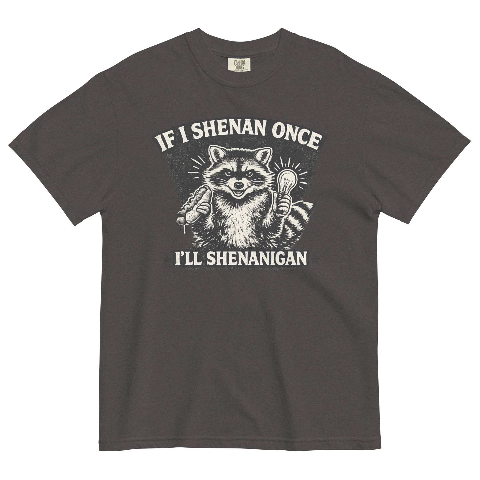 A graphite colored short-sleeve crewneck t-shirt featuring a distressed black and white illustration of a smiling raccoon holding a hot dog in one paw and a glowing lightbulb in the other. Arched above the raccoon is text that reads 'IF I SHENAN ONCE', and below the raccoon is text flanked by stars that reads 'I'LL SHENANIGAN'.