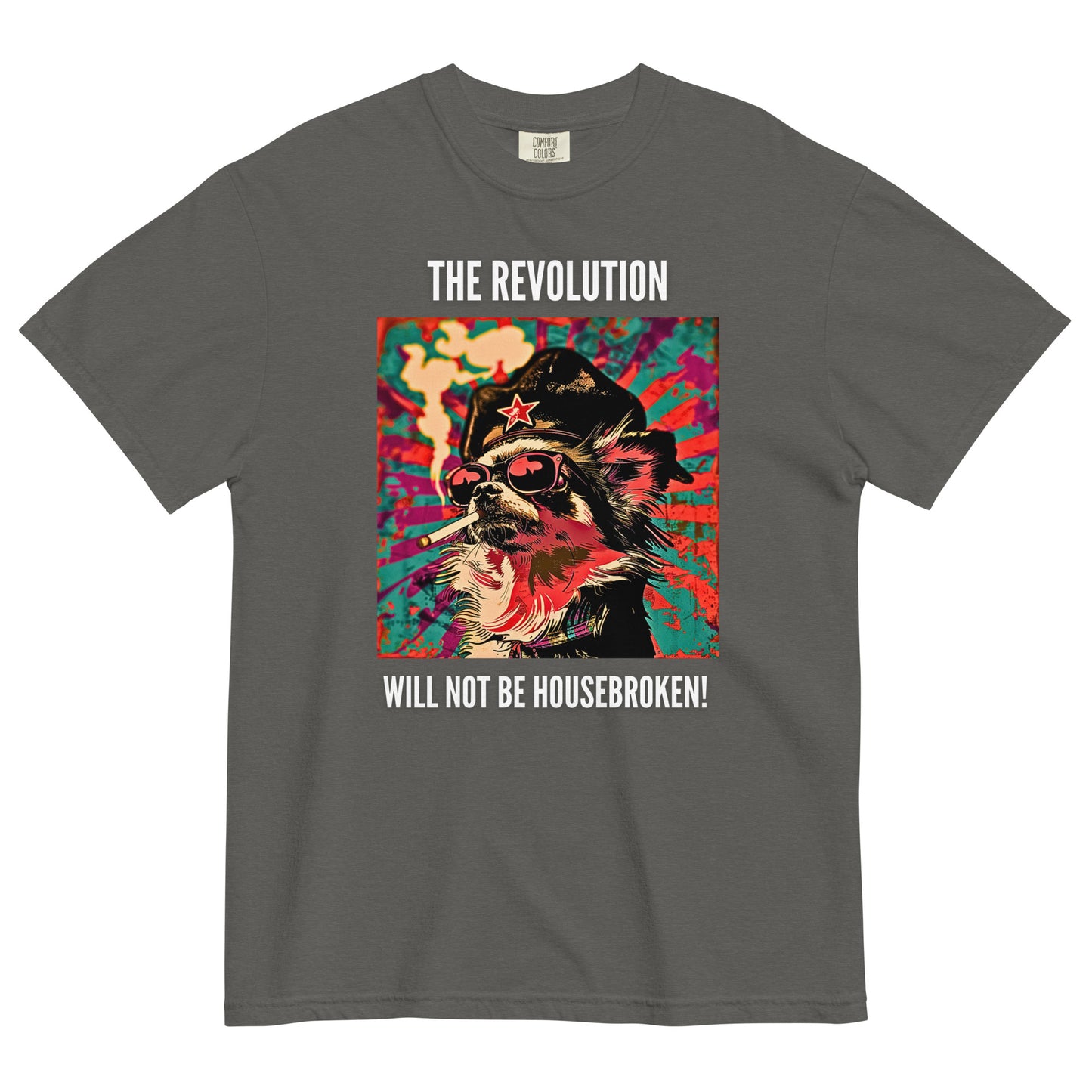 A pepper colored short-sleeve crewneck t-shirt featuring a vibrant, pop-art style square graphic on the chest. The illustration shows a long-haired Chihuahua stylized as a revolutionary, wearing a black hat with a red star, red-tinted sunglasses, and smoking a cigarette, set against a colorful, grunge-textured teal and red sunburst background. Above the graphic in white capital letters is the text 'THE REVOLUTION', and below it reads 'WILL NOT BE HOUSEBROKEN!'.
