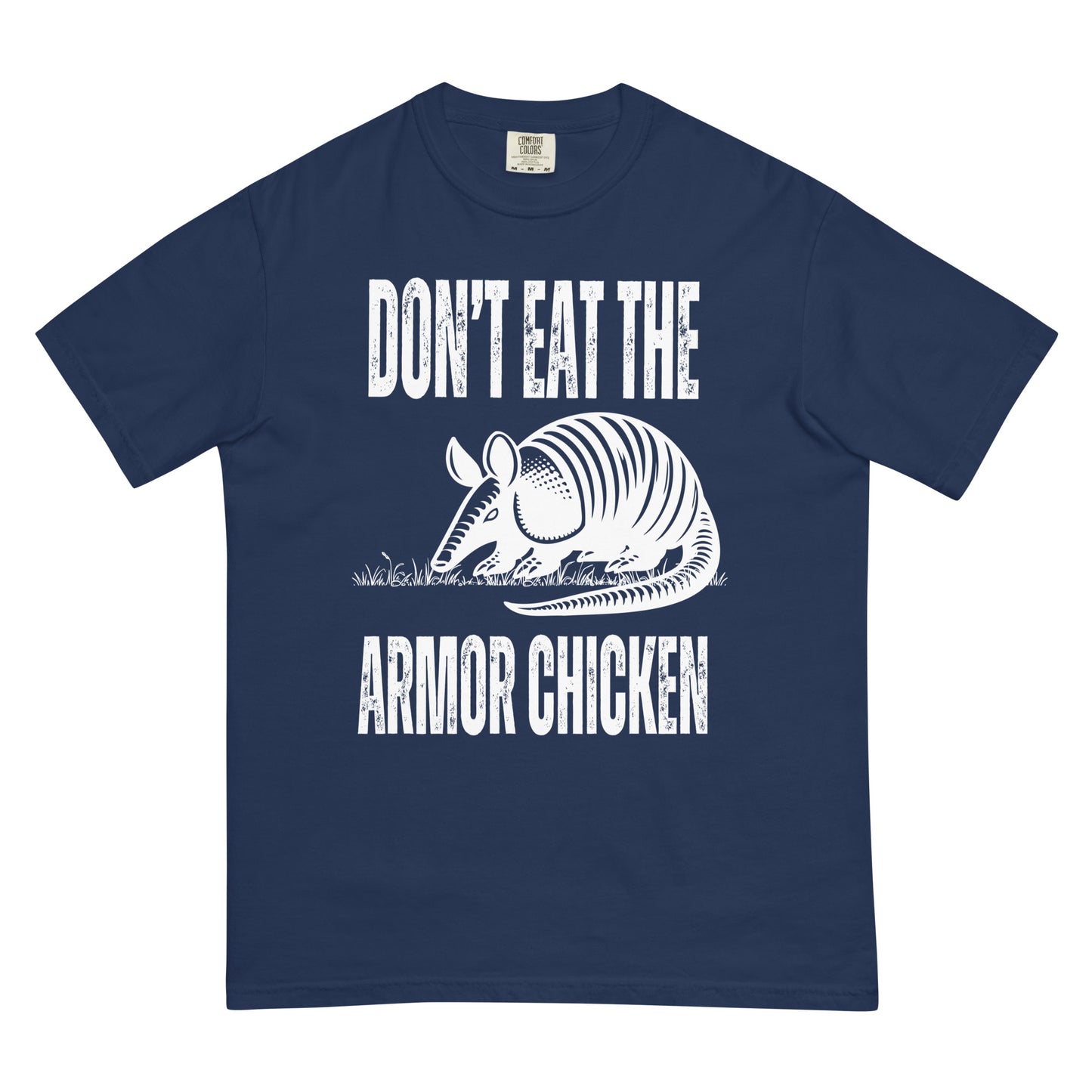 A true navy colored t-shirt with bold, all-caps, distressed white text that says 'DONT EAT THE ARMOR CHICKEN'. The text is separated into two lines by a white, line drawing graphic of an armadillo eating grass. 