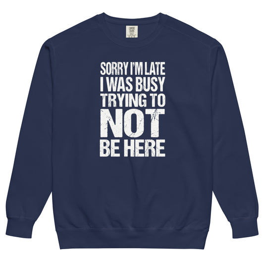 A true navy colored sweatshirt with an all-caps, distressed, white text graphic reading "SORRY I'M LATE I WAS BUSY TRYING TO NOT BE HERE" stacked in a rectangle on the chest. 